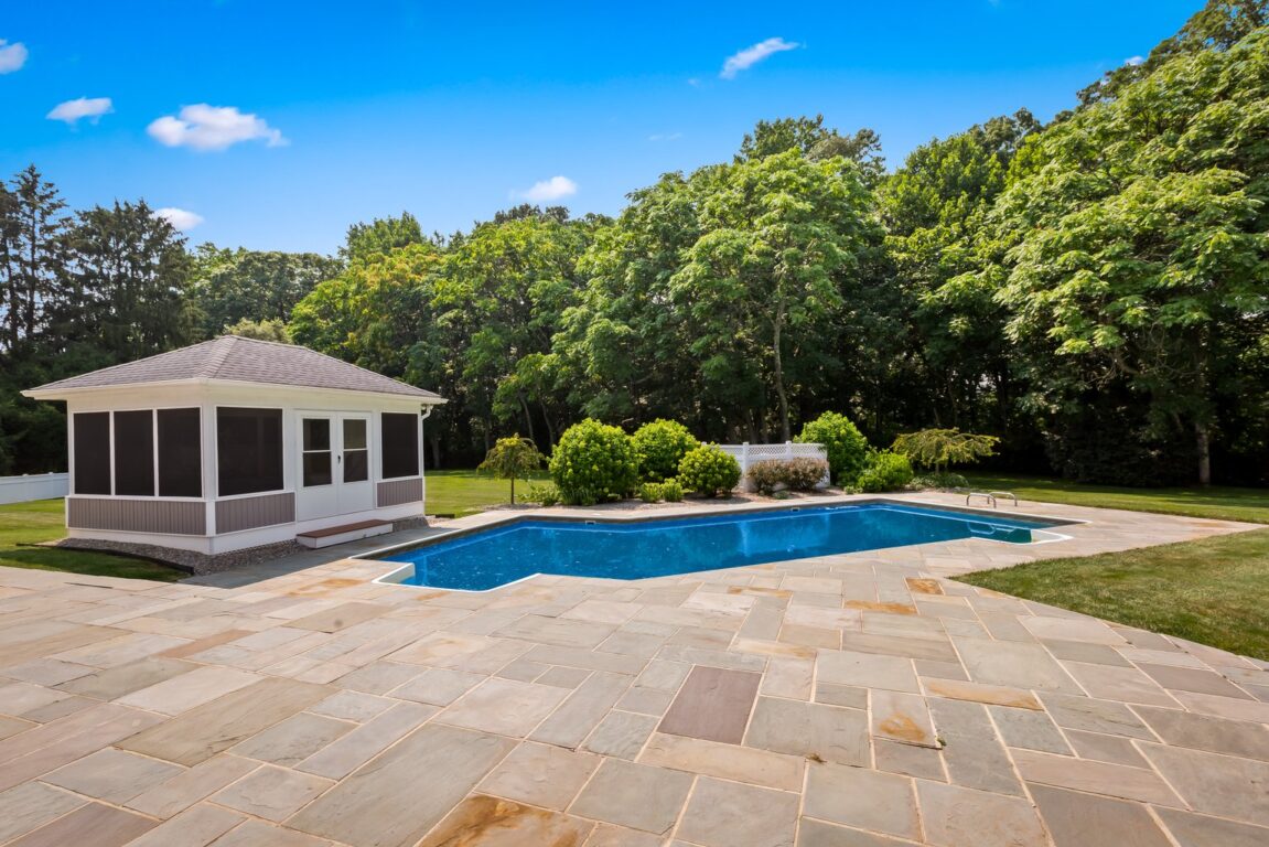 11324 Cedar Lane, paving stones, pool house and pool with trees in the background.