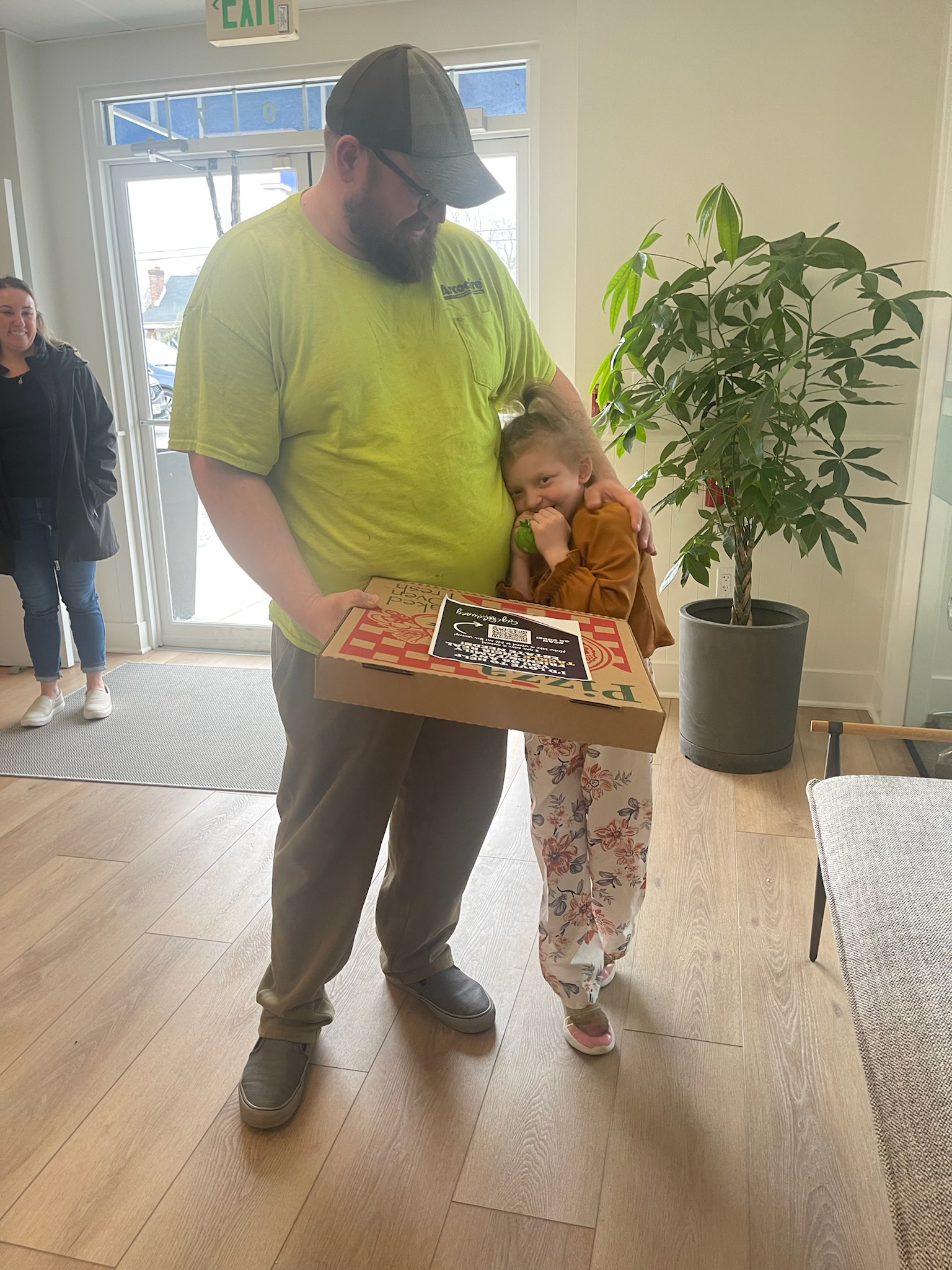 a man and his shy daughter getting their pizza.
