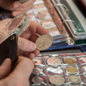 Looking at a coin through a magnifying glass with lots of coins in glassine sleeves in the background.