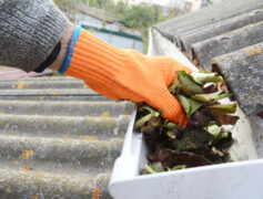 A gloved hand cleaning a gutter